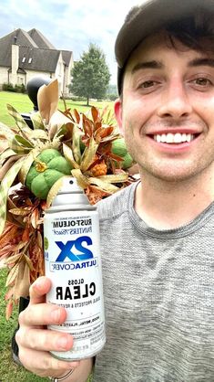 a man is holding up a spray bottle with flowers in it and smiling at the camera