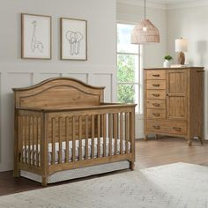 a baby crib in a room with two pictures on the wall and a dresser