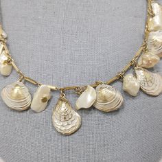 *Description: This is a white enamel over gold tone sea shell charm necklace with real or faux baroque pearls and 8mm faux pearls on the extension chain from the 1950s. This necklace has the same charms as a Napier necklace without the white enamel. I can not find another one like it. This is very similar to this Napier necklace with the same shape of clam and oyster shells but this necklace is unsigned. The pearls may be real baroque or may be faux. No matter which is accurate, it is a wonderfu Vintage Gold Jewelry With Pearl Charm, Vintage Shell Gold Jewelry, Vintage Gold Shell Jewelry, Vintage Shell Jewelry For Gifts, Vintage Pearl Necklace With Metal Pearl Charm, Vintage Shell Jewelry For Gift, Vintage Gold Shell As Gift, Vintage Gold Shell Gift, Vintage Gold Shell As A Gift