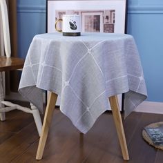 a table with a coffee cup on it next to a wooden chair and framed photograph