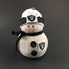 a knitted snowman wearing a oakland football hat and scarf with buttons on it