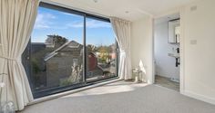 an empty room with a large window overlooking the street and houses in the back ground