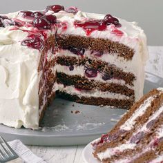 a cake with white frosting and cherries is cut from the side on a plate