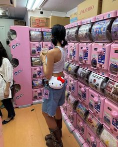 a woman is standing in front of pink vending machines with hello kitty on them