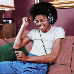 a young man sitting on top of a couch wearing headphones