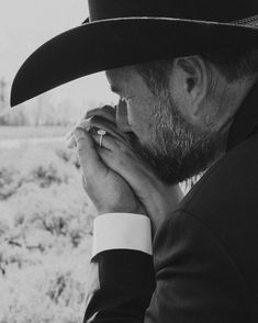 a man wearing a hat and holding his hands to his face while standing in the desert