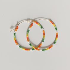 Colorful glass tropical, orange, green, and white beads adorn a gold hoop earring. These are lightweight and versatile earrings. Multicolor Hoop Earrings For Summer, Vibrant Colorful Beaded Earrings For Beach, Vibrant Beaded Earrings For The Beach, Trendy Multicolor Nickel-free Beaded Earrings, Colorful Beads Hoop Earrings For Beach, Colorful Beaded Hoop Earrings For Beach, Beach Hoop Earrings With Dangling Beads, Trendy Multicolor Hoop Earrings For Festivals, Colorful Beaded Hoop Earrings For Summer Festival