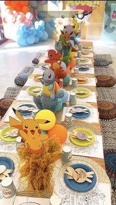 a long table with plates, cups and napkins on it is decorated with pokemon characters