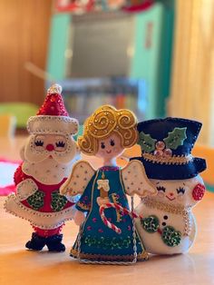 three snowmen are standing next to each other on a table in front of a christmas tree