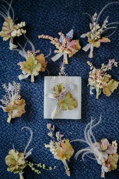 flowers and leaves are arranged on a blue carpeted surface, with small white squares in the middle