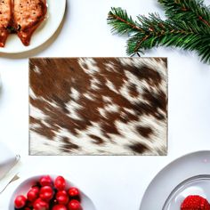 a table topped with plates and food covered in animal hide print next to christmas decorations