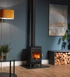 a wood burning stove in a living room next to a table with a lamp on it