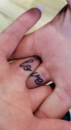 two fingers with the word love written on them and one hand holding another's finger