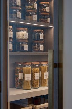 the shelves are filled with many different types of food in glass containers and labeled with labels