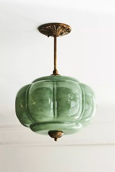 a green glass light fixture hanging from a ceiling