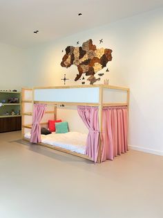 a bed with pink curtains and a map on the wall above it in a bedroom