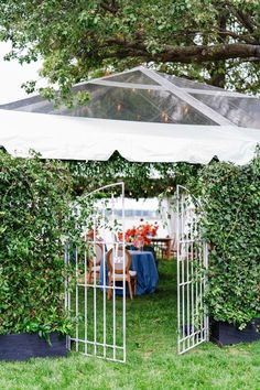 an outdoor dining area is set up with chairs and tables under a white gazebo