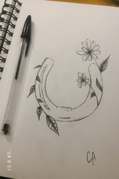 a drawing of a horseshoe with flowers and leaves on it, next to a pen