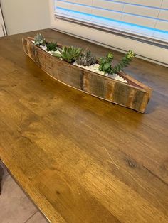 a wooden planter with succulents in it on top of a table