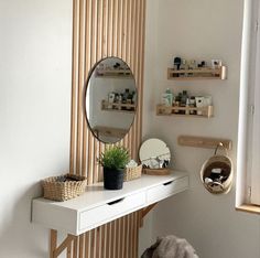 a white desk with a mirror and some shelves on the wall next to a potted plant