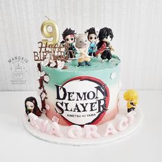 a birthday cake decorated with figurines and the name demon slayer