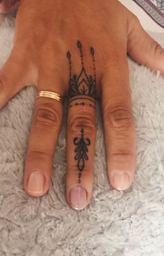 a woman's hand with a small tattoo on the middle finger and an ornate ring