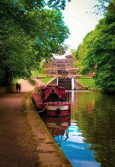 a red boat floating down a river next to a lush green forest