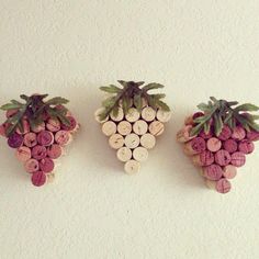 three wine corks are arranged in the shape of grapes and pineapples on a white wall