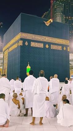 many people in white robes are around the ka'bah, with one person kneeling down