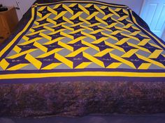 a bed with a purple and yellow quilt on it