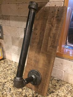 an old pipe is mounted to the side of a wooden board on a counter top