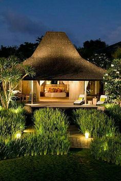 an outside view of a house with lights in the grass and plants around it at night