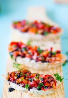 three pieces of bread with various toppings on them sitting on a cutting board next to each other