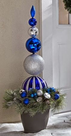 a potted plant with blue and silver ornaments on it's top, in front of a door