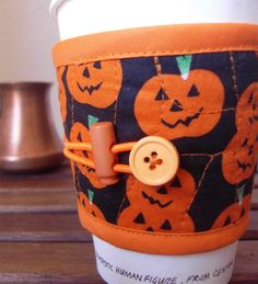 a coffee cup sleeve with pumpkins on it and a button in the middle,