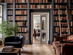 a living room filled with furniture and lots of books on the shelves in front of it