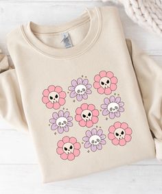 a t - shirt with skulls and flowers on it sitting next to a knitted hat