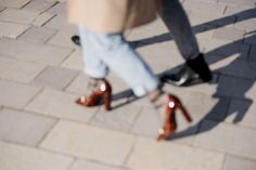 two people wearing high heeled shoes walking down the street