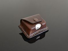 a brown leather case sitting on top of a black table next to a white button