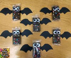 four halloween candy bags in the shape of bats with googly eyes and sprinkles