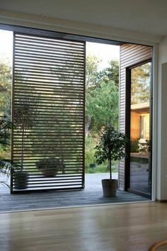 an open sliding glass door with potted plants on the outside and wooden flooring