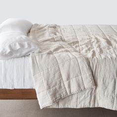 an unmade bed with white sheets and pillows