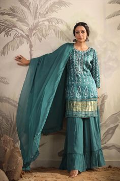 Featuring a teal color kurti in gajji silk base with zari, gota patti, thread, sequins and stones hand embroidery. Printed Kurti with poly crepe lining. It is paired with matching georgette tiered sharara pants with poly crepe lining and a silk chiffon dupatta with fringes for a touch of elegance. Gajji silk kurta, Georgette sharara, Silk chiffon dupatta Lining: Cotton Voile Occasion: Festive Ethnic Motifs Print Pattern Ornamentation: Beads And Stones Kurta Length: 36"-37" Sharara Length: 38" Sl Gajji Silk Kurta, Phulkari Pants, Color Kurti, Lucknowi Kurta, Kurta Skirt, Georgette Sharara, Gharara Suits, Bandhani Sarees, Patiala Salwar Suits