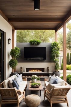 an outdoor living area with couches, chairs and a television on the wall above