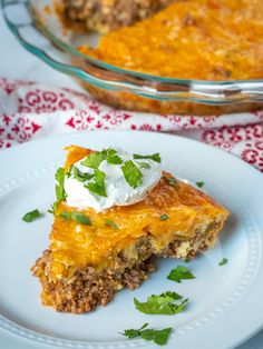 a slice of mexican meat pie on a white plate next to a casserole dish