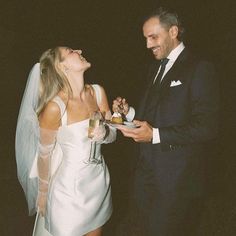 a man in a tuxedo and a woman in a wedding dress are laughing at each other