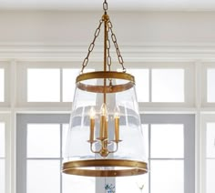 a chandelier hanging from the ceiling in a room with windows and white walls