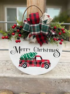 a christmas sign hanging from the side of a wooden pole with red and green decorations