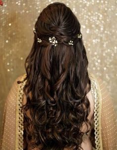 the back of a woman's head with long wavy hair and gold accessories on her head