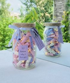 two jars filled with candy and lights on top of a table